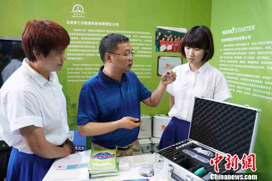 中科院国家纳米科学中心项目开发负责人任红轩(中)现场介绍纳米科普教具。 潘旭临 摄 北京科博会开幕 纳米科普引关注