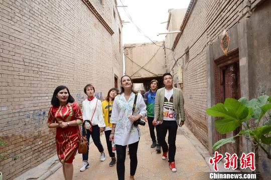 卡迪尔亚·卡布力孜正带着游客们参观喀什老城,向游客们介绍喀什老城的建筑特点。 勉征 摄 新疆喀什老城的文艺新玩法:游客学习木雕